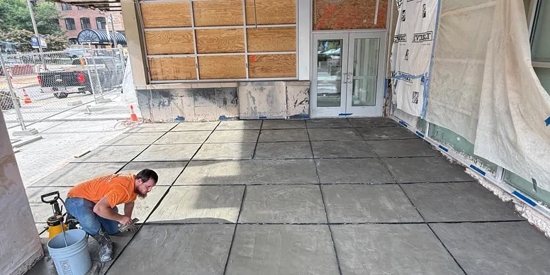 Installer hand-troweling a new terrazzo entryway floor at a storefront